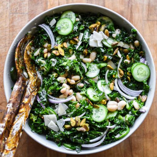 Kale and White Bean Salad in a bowl with serving utensils.