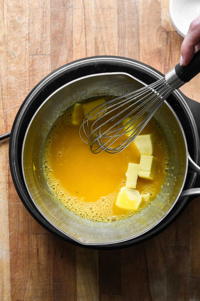 Adding egg yolks and butter to the fruit sugar mixture.