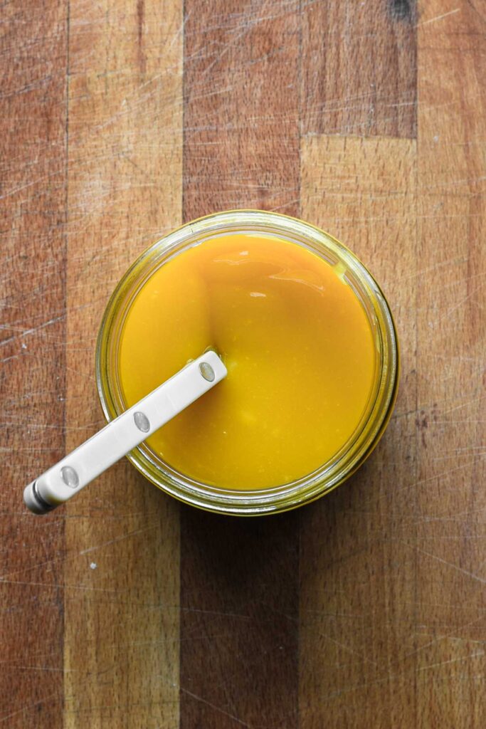 Curd in a glass jar with a white spoon.